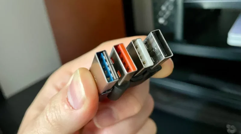 Ruka drži tri USB konektora sa plavim, crvenim i crnim unutrašnjim delom koji ilustruju razlike između USB portova