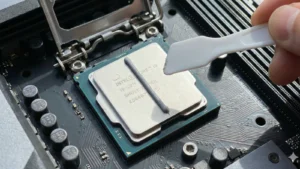 Kako pravilno naneti termalnu pastu na procesor: Kompletan vodič za 2025. 3 Krupni plan nanošenja termalne paste u obliku linije na Intel Core i9 procesor, sa belom plastičnom špatulom u ruci spremnom za razmazivanje.