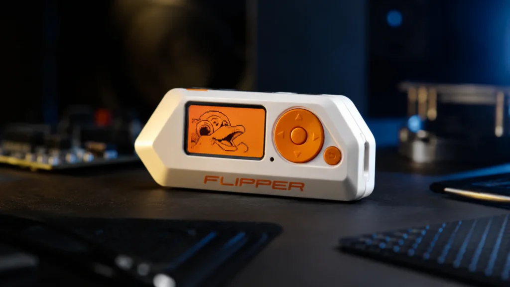 Flipper Zero uređaj na tamnom stolu uz modernu tehnološku opremu i osvetljenje
