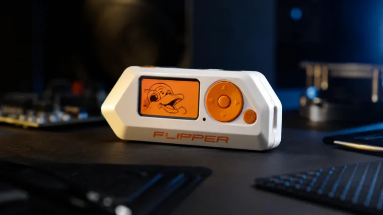 Flipper Zero uređaj na tamnom stolu uz modernu tehnološku opremu i osvetljenje