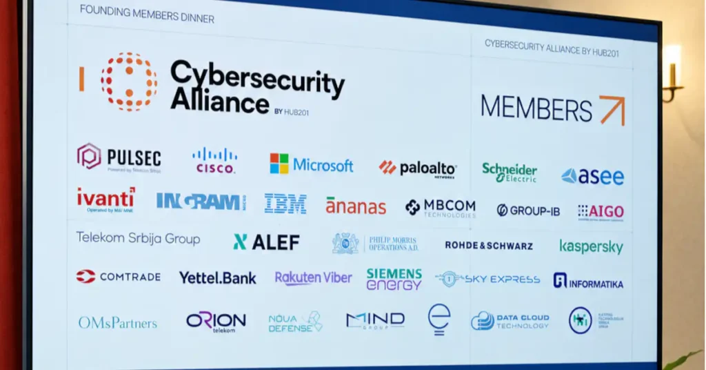 Veliki ekran na događaju "Founding Members Dinner" prikazuje logo "Cybersecurity Alliance by HUB201" i mrežu logotipa osnivačkih članova, uključujući Microsoft, Cisco, IBM, Visa, Schneider Electric i druge, sa nekoliko učesnika u prvom planu.