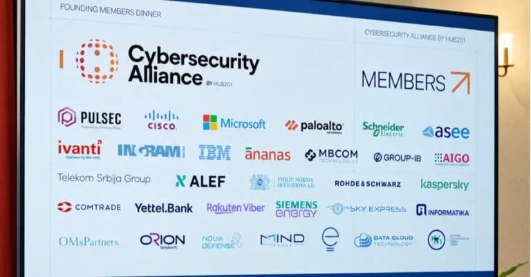Veliki ekran na događaju "Founding Members Dinner" prikazuje logo "Cybersecurity Alliance by HUB201" i mrežu logotipa osnivačkih članova, uključujući Microsoft, Cisco, IBM, Visa, Schneider Electric i druge, sa nekoliko učesnika u prvom planu.